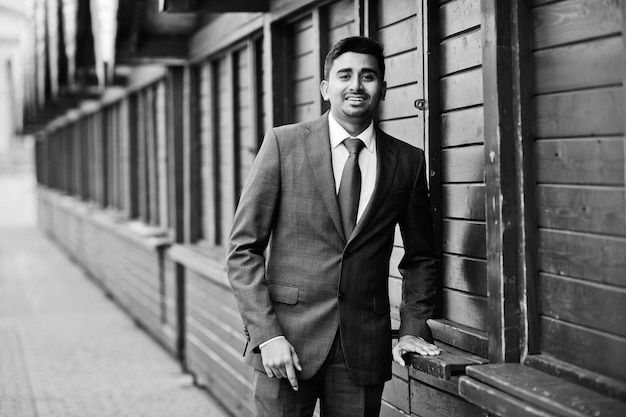 Elegant indian fashionable man model on suit posed against wooden stalls