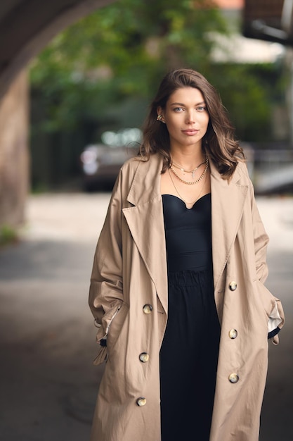 Elegant jong meisje in een beige regenjas die buiten poseert