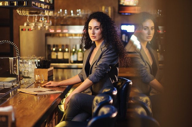 Elegante signora in tailleur, in un ristorante al bancone di un bar da sola