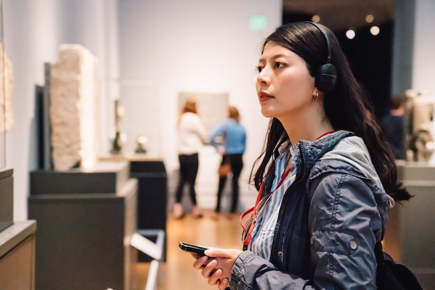 an elegant lady in the exhibition, wearing earphone to hear the voice guide