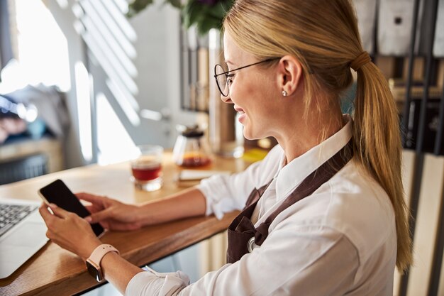 Signora elegante che guarda lo schermo del cellulare al chiuso