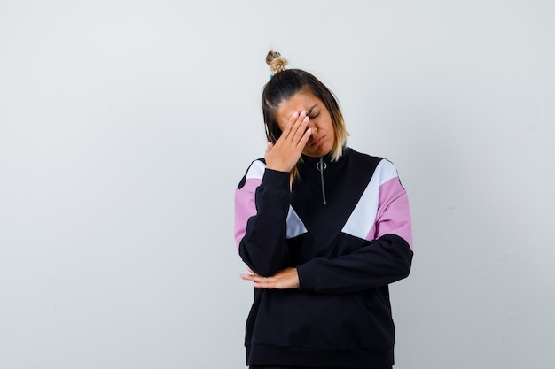 Elegant lady rubbing forehead, keeping eye shut in sweatshirt and looking exhausted