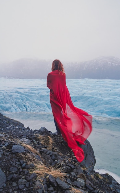 Elegant lady with red fabric on rock scenic photography