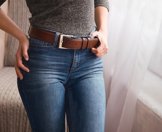 Elegant, leather, brown belt on a belt with a metal buckle for a girl. Original handmade leather clothing accessory