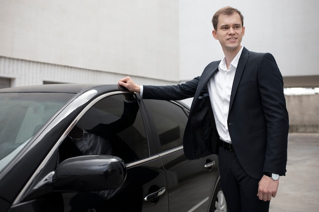 Photo elegant man standing next to his car for taxi services