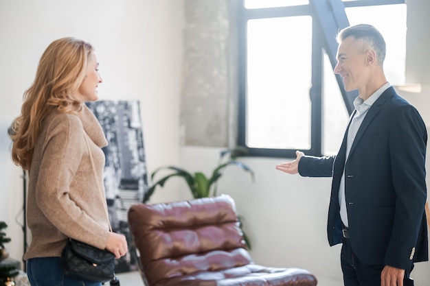 Photo elegant man in a suit talking to a blonde woman in the office