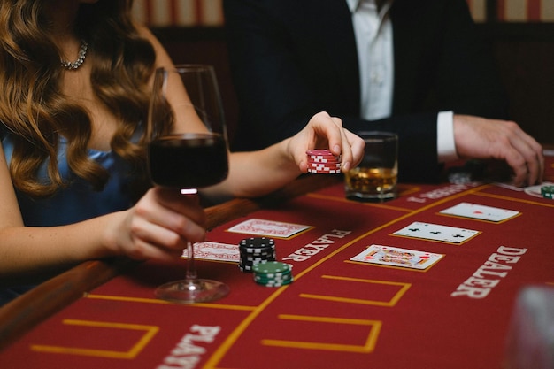 Foto uomo e donna eleganti che giocano a poker in un casinò e bevono vino