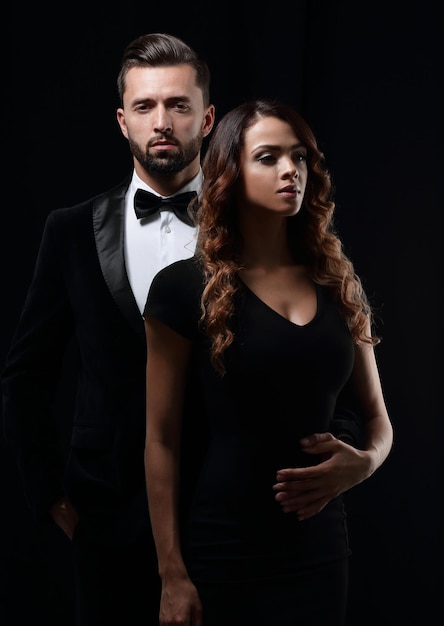 Elegant man and woman posing next to each other on studio