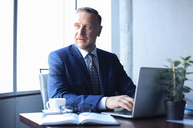 Elegant mature businessman analyzing data while working in office.