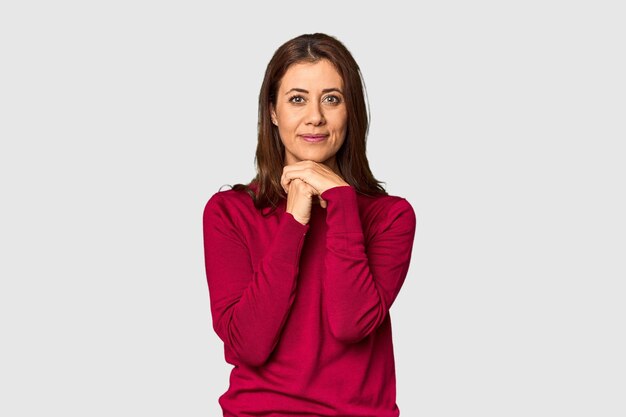 Elegant middleaged Caucasian woman in studio setting praying for luck amazed and opening mouth