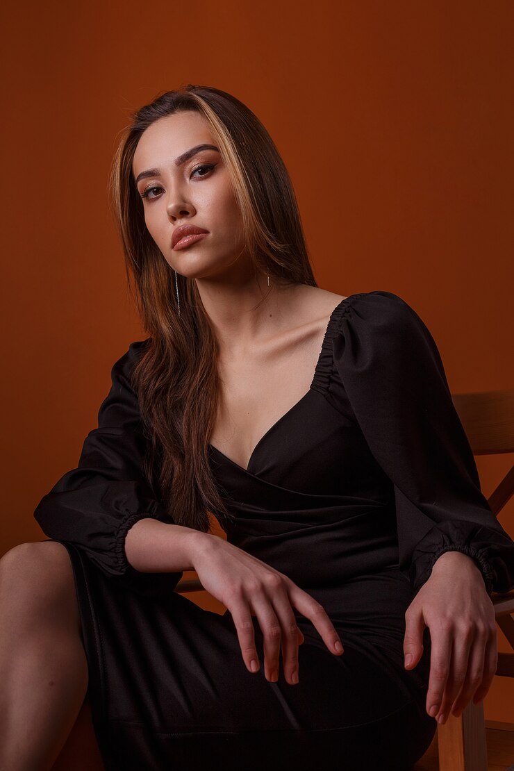 Photo elegant model wearing black dress and high heels shoes posing on red