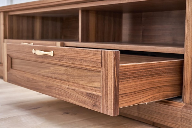 Elegant new TV cabinet made of veneer and solid walnut lumber with open drawer low angle close view