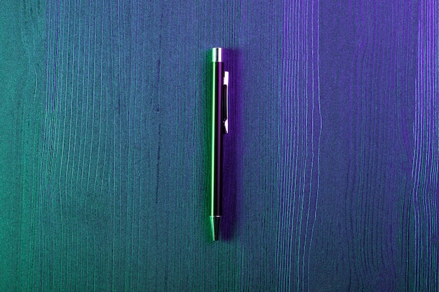 Elegant pen on wood and green and blue light. Business black pen. Top view