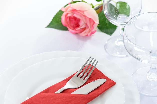 Elegant restaurant table setting for a romantic dinner with rose plates cutlery and stemware