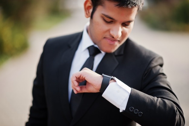 Elegant south asian business man in suit looking at his smart watches on hand.