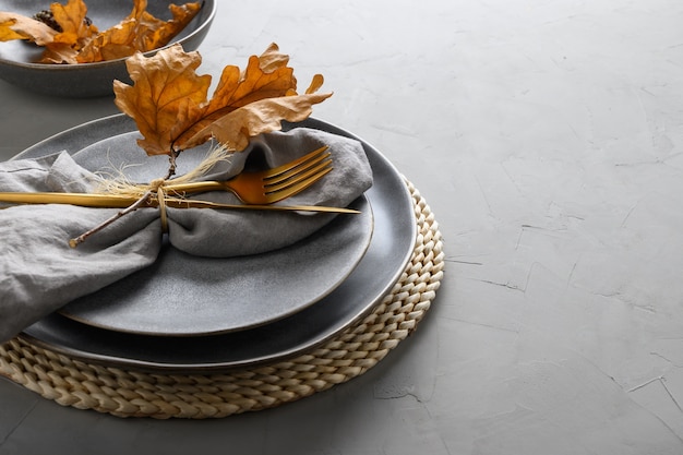 Photo elegant table setting with autumn oak leaves and golden cutlery.