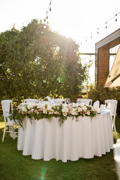 Elegant table setting with flower arrangement at outdoor wedding reception.