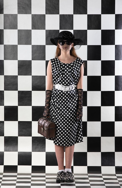 elegant teenage girl in polka dress on a chess background