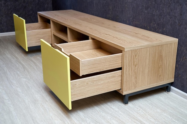 Elegant TV stand made of oak wood veneer with bright yellow facade and open drawers in minimal style