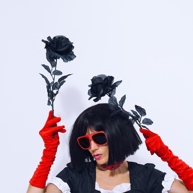 Elegant vampire gothic Lady in red gloves holding black roses