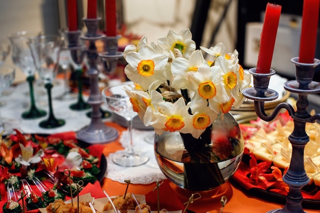 Elegant vase with bouquet of daffodils to decorate the dining table Beautiful festive table setting