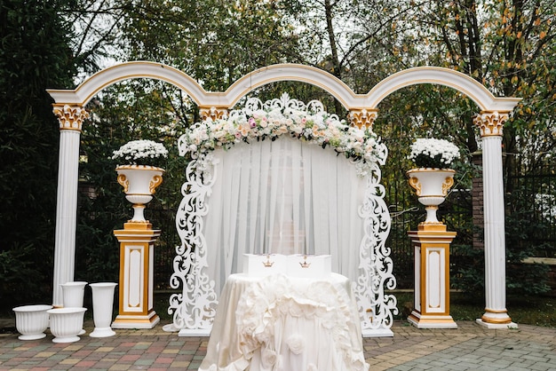 Elegant wedding arch with fresh flowers vases on background of forest Arch decorated pink roses and white flowers standing in the woods in the wedding ceremony area Wedding decor