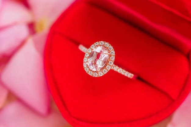 Elegant wedding diamond ring in red heart jewelry box on beautiful pink rose petal background