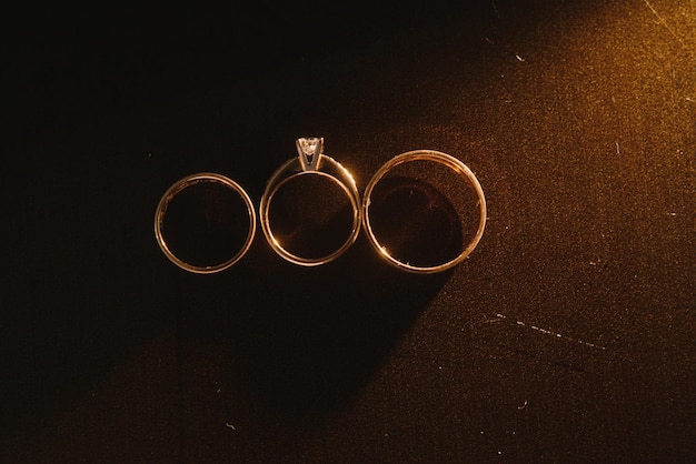 Фото Элегантные обручальные кольца для жениха и невесты на черном фоне с бликами макроселективного фокуса