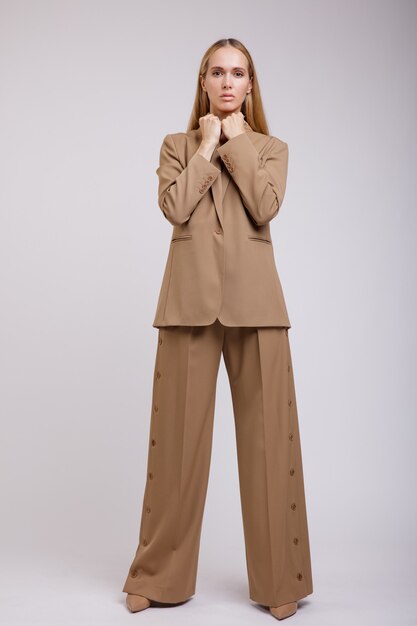 Elegant woman in beige brown suit buttondown pants jacket on white background Slim figure