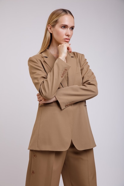 白い背景の上のベージュの茶色のスーツボタンダウンパンツジャケットのエレガントな女性スリムな図