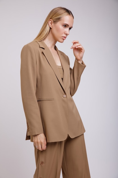 Elegant woman in beige brown suit buttondown pants jacket on white background Slim figure