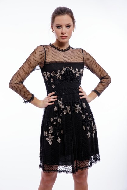 Elegant woman in black dress with lace posing on white background