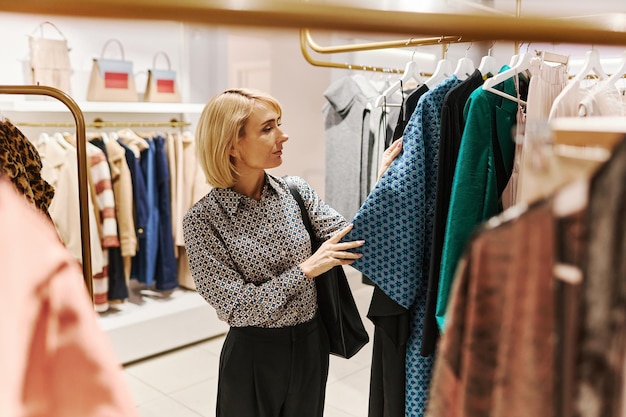 Elegant woman choosing clothes in boutique shopping mall