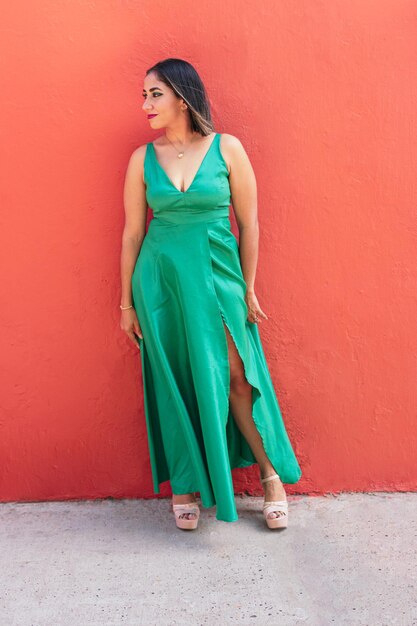 Элегантная женщина в модном зеленом платье на фоне стены на улице
