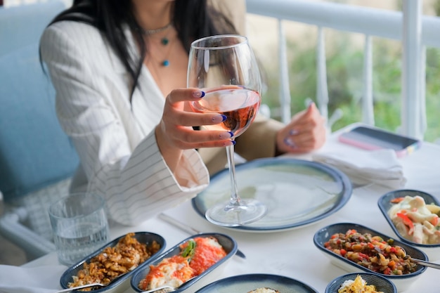 An elegant woman holding a pink wine glass at the seafood restaurant.