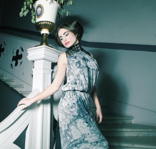 Elegant woman in long dress on vintage stairs