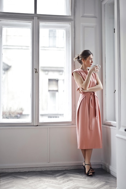 Foto donna elegante che guarda fuori dalla finestra