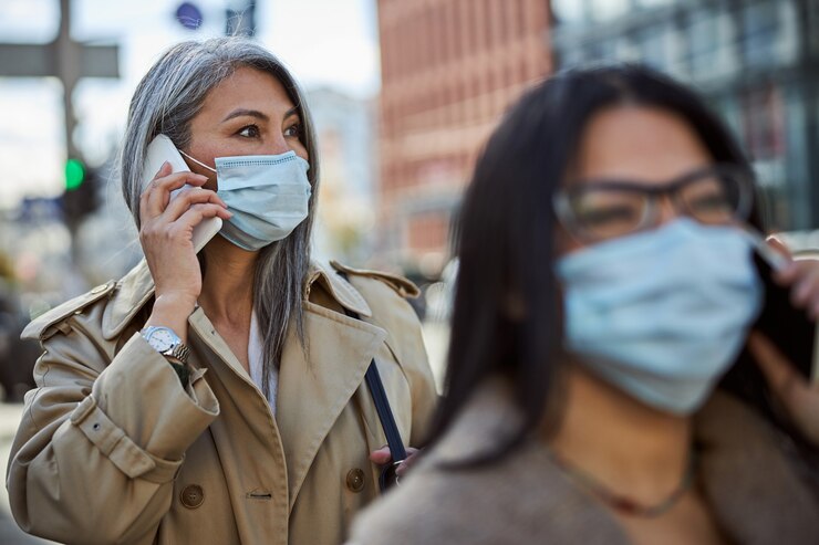 Photo 屋外で電話で会話する医療マスクのエレガントな女性