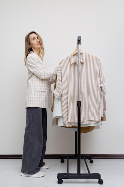 Elegant woman near minimalist slow fashion Clothes rack