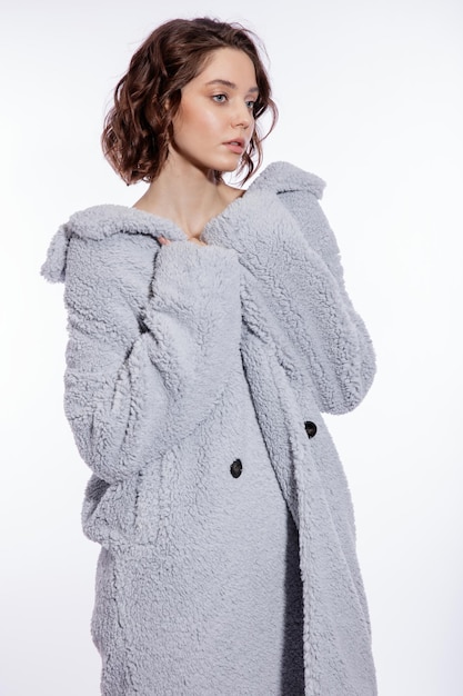 Elegant woman in pale blue fur coat suede boots posing over white background Make up hairstyle