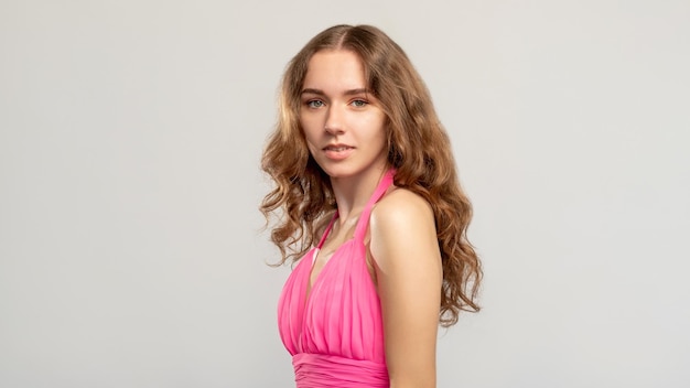 Photo elegant woman portrait feminine beauty tender brunette lady in pink with curly hair natural makeup looking at camera isolated on neutral empty space background
