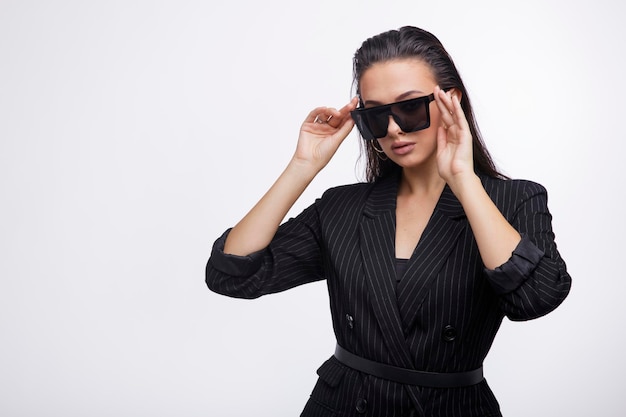 Elegant woman in pretty black jacket, leather pants, boots,\
sunglasses on white background.