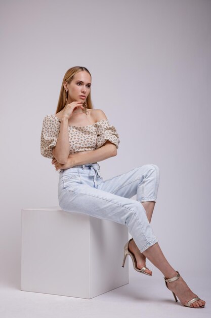 elegant woman in pretty blue denim jeans, beige with floral pattern top on white background