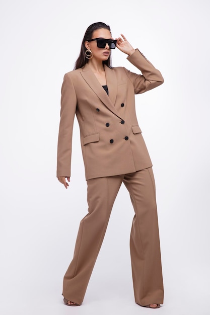 elegant woman in pretty brown and beige suit, jacket, pants on white background