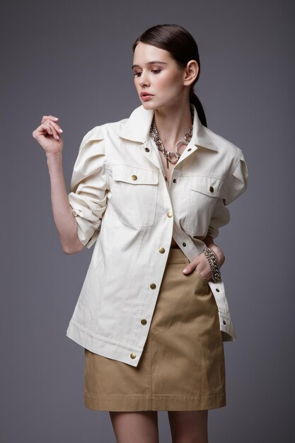 Elegant woman in pretty white shirt beige sand skirt  accessories  on gray background Studio Shot