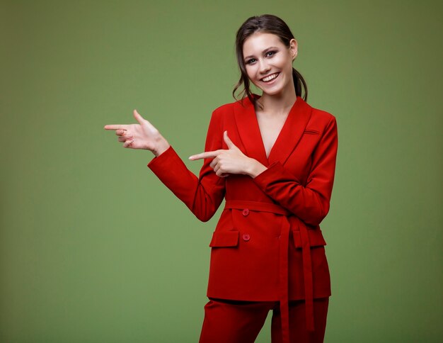 Elegant woman in red suit jacket pants on green background Studio Shot Businesswoman