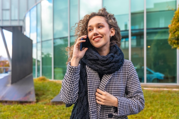 Photo elegant woman using phone in the city street in autumn