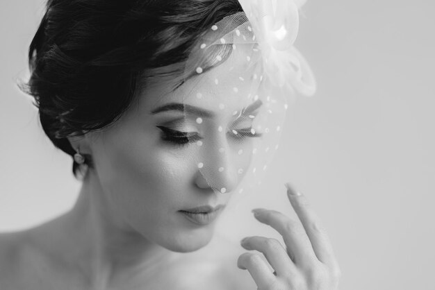 An elegant woman in veil hat posing for camera with closed eyes