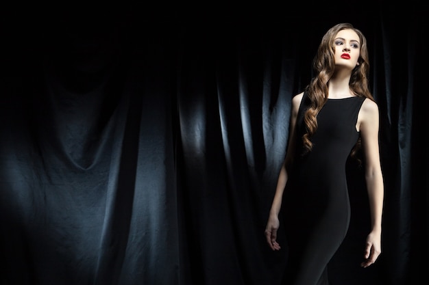 Elegant woman with long wavy hair against of black cloth