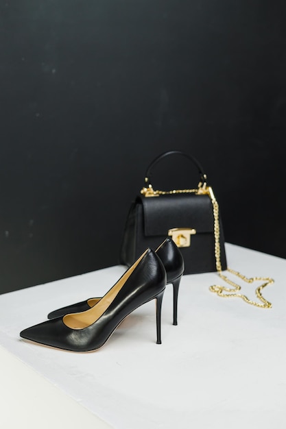 Elegant women's pumps with heels stand next to a black handbag on a white background Place for writing